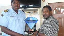 Acting Commander of the Coast Guard, Brenton Cain, presents a plaque to Commander Tyrone James.