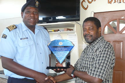 Acting Commander of the Coast Guard, Brenton Cain, presents a plaque to Commander Tyrone James.