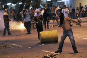 Supporters of Venezuelan opposition presidential candidate Henrique Capriles throw stones during a clash with police in Caracas on April 15. (Leo Ramirez/AFP/Getty Images)
