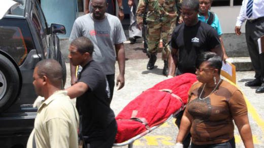 Police officers look on as funeral home employees remove Hamilton's body from the court building on Tuesday. (Internet photo)