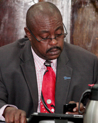 Minister of National Mobilisation, Frederick Stephenson uses handheld devices in Parliament on Friday.
