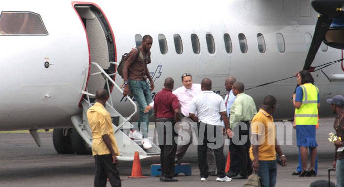 Wanted man Dwaine Sandy disembarks a LIAT flight from Grenada at the E.T. Joshua Airport as his lawyer, Grant Connell (facing camera) talks with police on Monday, June 17, 2013.