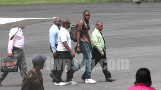 Dwaine Sandy (in brown) is escorted by police to the terminal building at the E.T. Joshua Airport shortly after arriving from Grenada on Monday, June 17, 2013. His lawyer, Grant Connell is furthers left and partly hidden. (IWN photo)
