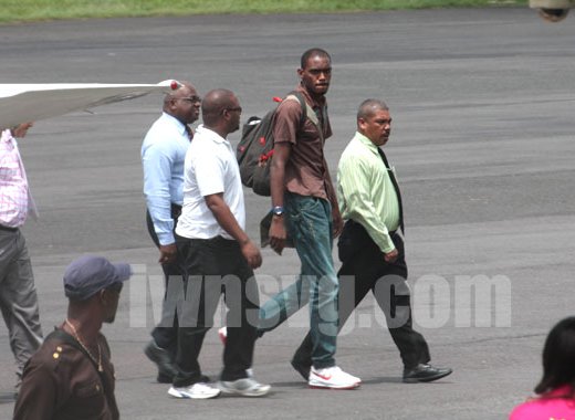 Dwaine Sandy (in brown) is escorted by police to the terminal building at the E.T. Joshua Airport shortly after arriving from Grenada on Monday, June 17, 2013. His lawyer, Grant Connell is furthers left and partly hidden. (IWN photo)