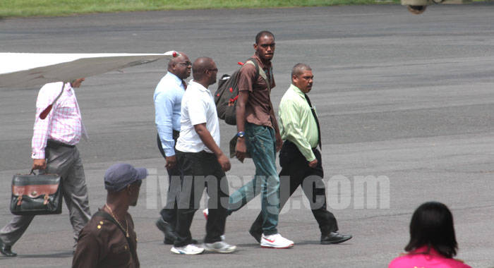 Dwaine Sandy (in brown) is escorted by police to the terminal building at the E.T. Joshua Airport shortly after arriving from Grenada on Monday, June 17, 2013. His lawyer, Grant Connell is furthers left and partly hidden. (IWN photo)