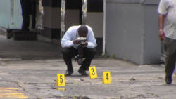 In this June 13, 2013 photo, a police photographer works at the scene where a cop was shot in Kingstown. (IWN photo)