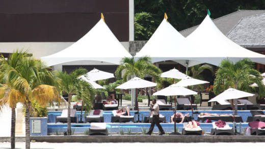 A security guard walks by as guests sunbathe at Buccament Bay Resort on July 4, 2013. (IWN photo)