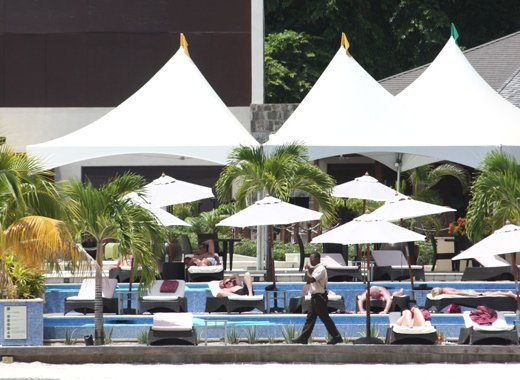 A security guard walks by as guests sunbathe at Buccament Bay Resort on July 4, 2013. (IWN photo)