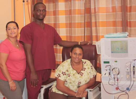 Managing Director of Health Solution Inc., Pauline Garabedian, left, and staff members, Keyon St. John, centre, and Kamora Bynoe, pose next to one of the dialysis machines at the facility. (IWN photo)  