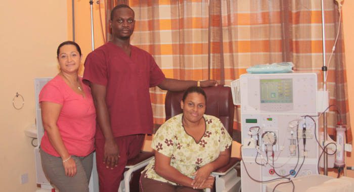 Managing Director of Health Solution Inc., Pauline Garabedian, left, and staff members, Keyon St. John, centre, and Kamora Bynoe, pose next to one of the dialysis machines at the facility. (IWN photo)  