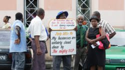 Businessman Leon "Bigger Biggs"  Samuel holds his placards while persons look on. (IWN photo)