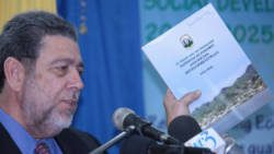 Prime Minister Dr. Ralph Gonsalves displays a copy of the Plan while making the feature address. (IWN photo)