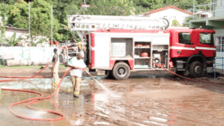 On Thursday, firefighters clean mud from the yard of the Buccament Bay Secondary School, were 53 persons were had sought refuge. (IWN image)  