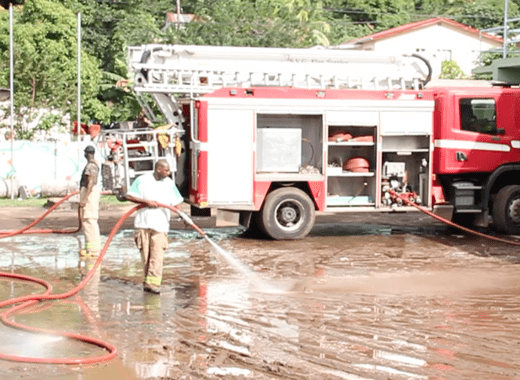 On Thursday, firefighters clean mud from the yard of the Buccament Bay Secondary School, were 53 persons were had sought refuge. (IWN image)  