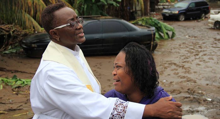 Rev. Eleanor Glasgow prays with Colleen James in Cane Grove on Wednesday, hours before it was confirmed that James' sister, Kesla, had died in flood waters. Her 2-year-old daughter is still missing. (IWN photo)