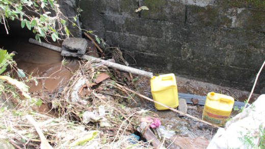 Water is funnelled into jugs in a gutter in Spring Village on Friday, Dec. 27, 2013. The Ministry of Health has warned against consuming contaminated water.  (IWN photo)