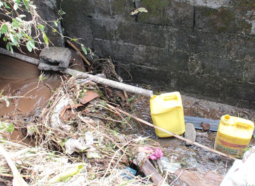 Water is funnelled into jugs in a gutter in Spring Village on Friday, Dec. 27, 2013. The Ministry of Health has warned against consuming contaminated water.  (IWN photo)