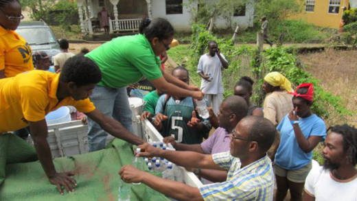 Opposition MPs Frederick, Matthews and Cummings, distribute water in North Leeward on Friday. (NDP photo)