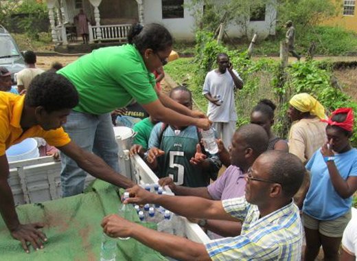 Opposition MPs Frederick, Matthews and Cummings, distribute water in North Leeward on Friday. (NDP photo)