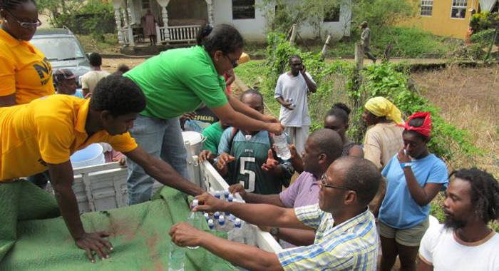 Opposition MPs Frederick, Matthews and Cummings, distribute water in North Leeward on Friday. (NDP photo)