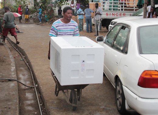 A man uses a wheelbarrow to move one of the stoves donated to disaster victims in Buccament Bay on Friday, Jan. 24, 2014. (IWN image) 