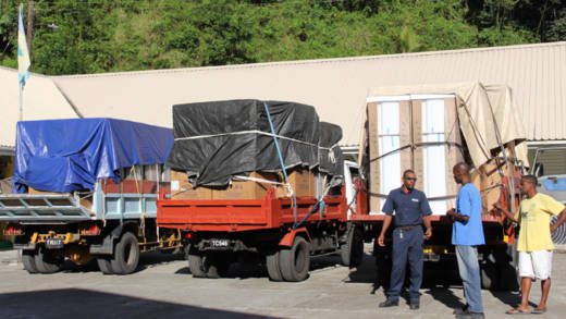 Trucks carrying fridges and stoves for disaster victims arrive at the Spring Village Primary School on Wednesday. NEMO says it has taken steps to prevent persons from claiming the same items more than once. (IWN photo)