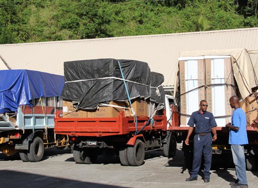 Trucks carrying fridges and stoves for disaster victims arrive at the Spring Village Primary School on Wednesday. NEMO says it has taken steps to prevent persons from claiming the same items more than once. (IWN photo)