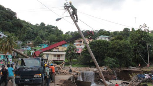 A worker repairs a damaged pole in North Leeward after the December 2013 floods. (iWN photo)
