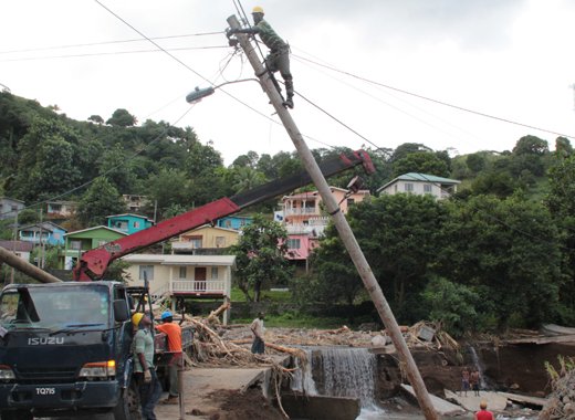 A worker repairs a damaged pole in North Leeward after the December 2013 floods. (iWN photo)