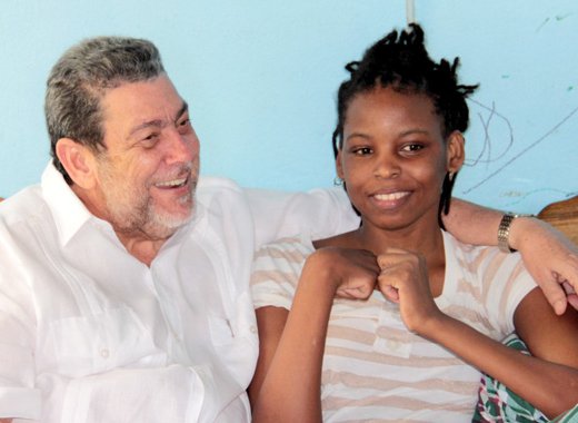 Prime Minister Ralph Gonsalves chats with Sweet-I Robertson at her home in Chateaubelair on Saturday. (IWN photo) 