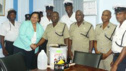 Manager of St. Vincent Cooperative Bank Laverne Velox, donates paint to Superintendent Kenneth John, head of the Traffic Department, while Commissioner of Police Michael Charles and other officers look on. 