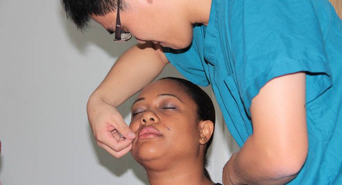 Taiwanese physician Dr. Shun-chang Ian Chang demonstrate acupuncture on a volunteer in Kingstown. (IWN photo)