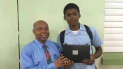 Student Ezra Adams receives a laptop from MP for West St. George, Cecil Ces McKie. (Photo: Camillo Gonsalves/Facebook)