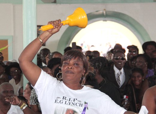 A woman rings a bell amidst jeering as PM Gonsalves is called to give a tribute at the funeral of Elwardo E.G. Lynch. (IWN photo) 