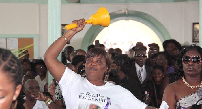 A woman rings a bell amidst jeering as PM Gonsalves is called to give a tribute at the funeral of Elwardo E.G. Lynch. (IWN photo) 