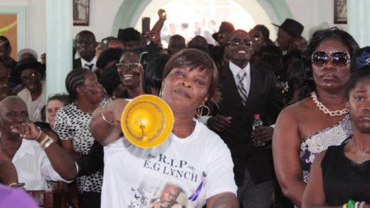 A woman rings a bell in protest against Gonsalves delivering a tribute at E.G. Lynch's funeral on July 19, 2014. (IWN photo)