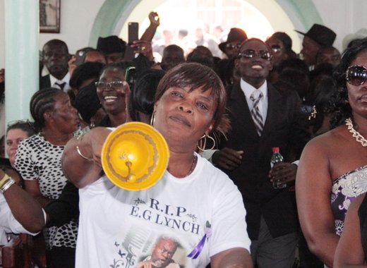 A woman rings a bell in protest against Gonsalves delivering a tribute at E.G. Lynch's funeral on July 19, 2014. (IWN photo)