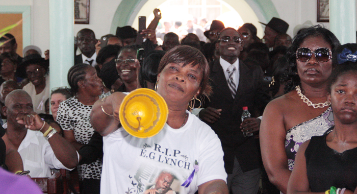 A woman rings a bell in protest against Gonsalves delivering a tribute at the funeral. (IWN photo)