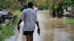 A fisherman walks through a flooded street in Buccament Bay on Sept. 6. (IWN photo)