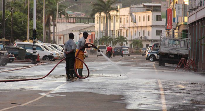 Firefighters use hoses to wash dust from Bay Street, Kingstown late Monday afternoon.  (IWN photo)
