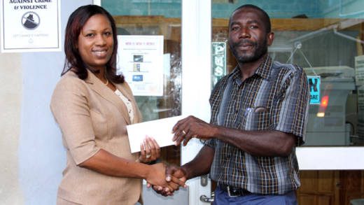 Seymonde Mulcaire, manager of PCCU presenting Kent Caine, manager of PCCU Bonhomme Stars with a cheque for the purchasing of uniforms.
