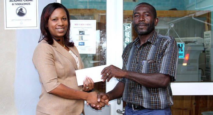 Seymonde Mulcaire, manager of PCCU presenting Kent Caine, manager of PCCU Bonhomme Stars with a cheque for the purchasing of uniforms.