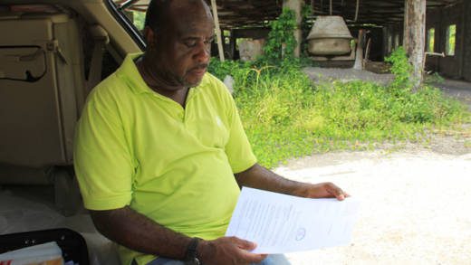 Businessman Leon "Bigger Bigs" Samuel looks over what he initially thought was his new mining licence. (IWN photo)