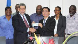 Prime Minister Gonsalves, right, receives the cheque from Ambassador Ger as senior health officials look on.