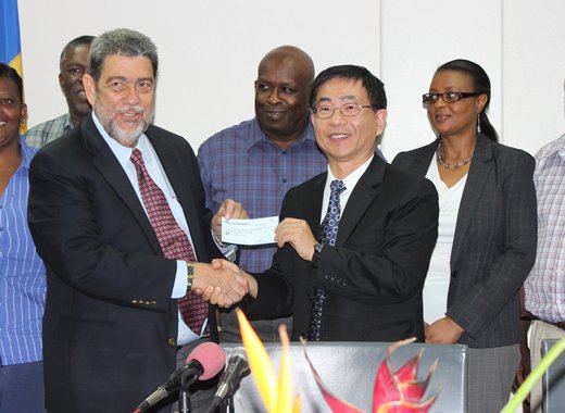 Prime Minister Gonsalves, right, receives the cheque from Ambassador Ger as senior health officials look on.