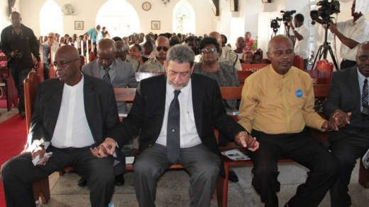 From left: Opposition Leader Arnhim Eustace, Prime Minister Ralph Gonsalves, and Pastor George Frederick join hands during prayer at the memorial service. (IWN photo) 