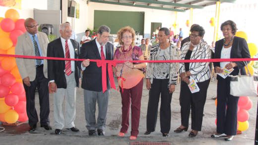 Officials looks on as Chair of ECBI, Audrey DeFreitas, prepares to cut the ribbon at the opening ceremony. (IWN Photo)