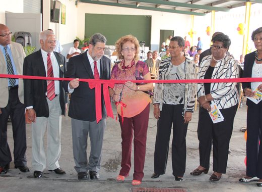 Officials looks on as Chair of ECBI, Audrey DeFreitas, prepares to cut the ribbon at the opening ceremony. (IWN Photo)