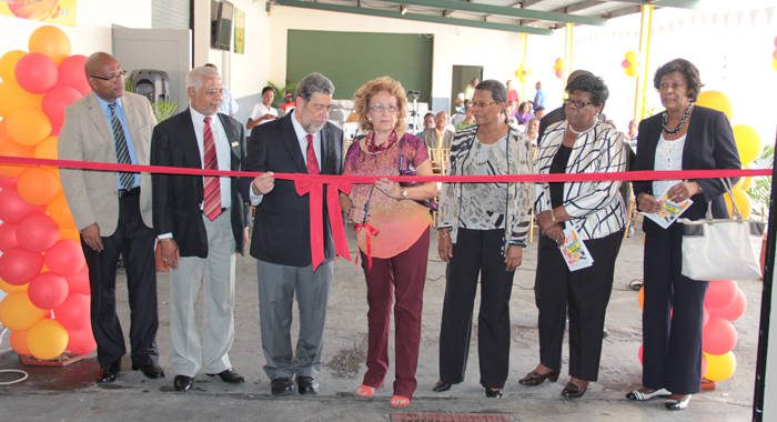 Officials looks on as Chair of ECBI, Audrey DeFreitas, prepares to cut the ribbon at the opening ceremony. (IWN Photo)