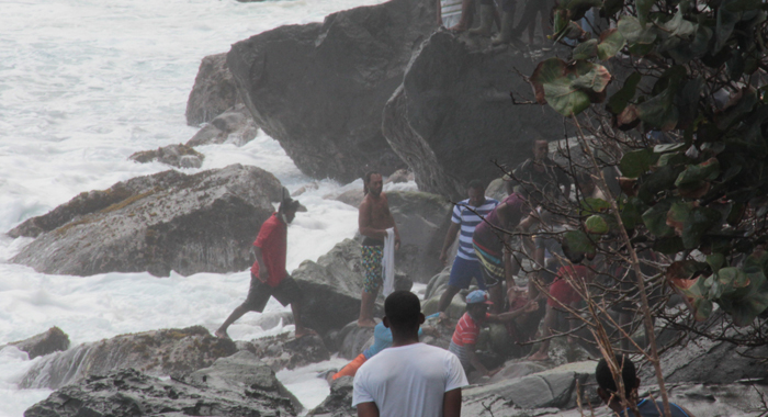 Civilians retrieve a body of one of the victims from the rough waters. (IWN photo)